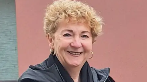 Positive Futures Agnes Lunny, a woman with blonde curly hair, wearing earrings and a black jacket.