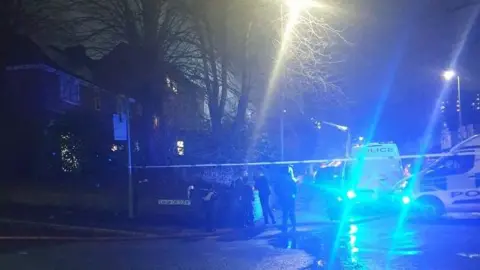 Bernie Sheerin Police vans gather at the cordon as they seal off a fire at a synagogue - crowds of young people are watching on 