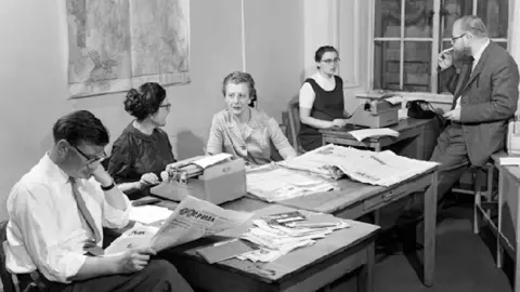 Journalists reading newspapers in an old 1970s picture