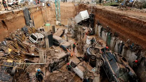 EPA Civil Guard officers search for survivors inside cars trapped under the foundations of a building
