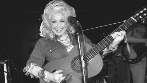 Getty Images Dolly Parton, pictured in black and white, rehearsing for her New York nightclub debut at the West Village's Bottom Line in 1977
