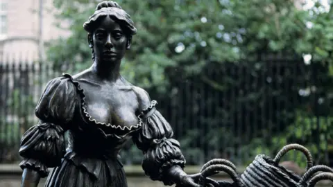 Andy Sotiriou/Getty Images The statue of Molly Malone at its original site in Dublin's Grafton Street. The gates of Trinity College are in the background.