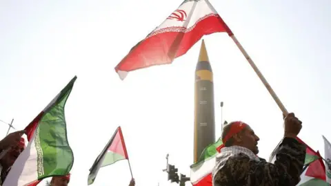 EPA Iranians holding the national flag and red bandanas on their heads with a missile pointing skywards