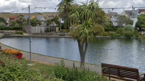 The boating lake at Perranporth with a palm tree and a bench