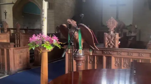 Handout The wooden eagle before the incident. The animal carving is sat on a wooden plinth with green ribbon wrapped around its wings.