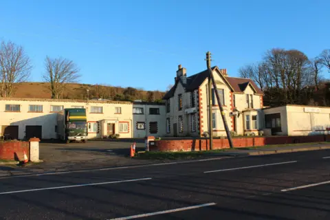 Billy McCrorie A white-fronted hotel building surrounded by a low brick wall with a striking blue sky overhead