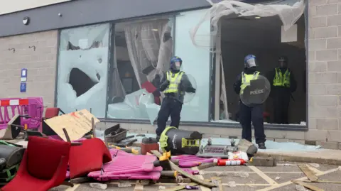 Reuters Police officers stand near the broken windows of the hotel during an anti-immigration protest, in Rotherham, Britain.