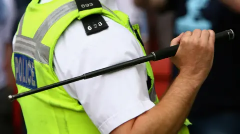 A police officer holding an extendable baton