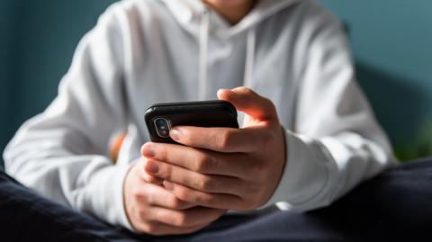 Close up of hands of teen boy texting on phone