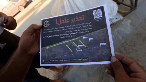 Reuters A man holds a leaflet from the Israeli military that warns all residents of Gaza City to leave immediately, in Gaza City (9 September 2025)