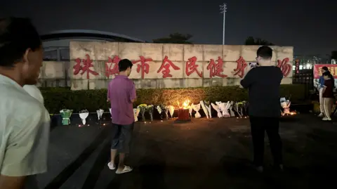 Reuters Mourners bow their heads while visiting the stadium on Tuesday, where a string of floral tributes line the perimeter