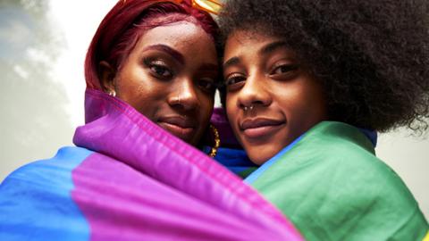 Two women draped in a rainbow flag