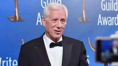 Getty Images Portrait of James Woods in a suit on a red carpet. A blue background has the words guild rewards repeated several times behind it.