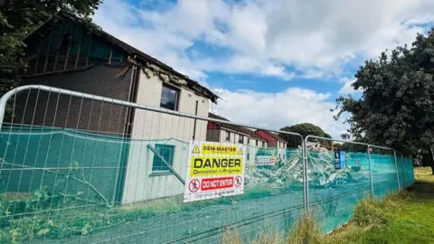 Demolished houses in Aberdeen, due to the presence of potentially dangerous concrete, with a fence outside and danger warning sign.