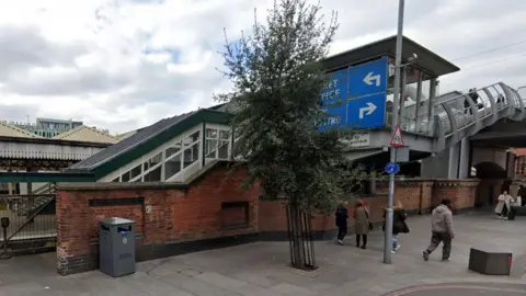 A streetview image of the staircase on to the footbridge, also showing tram line access