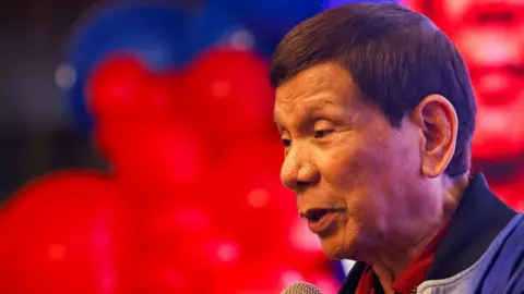 Close up, side view photo of former Philippine President Rodrigo Duterte days before his arrest, against a blurred red background