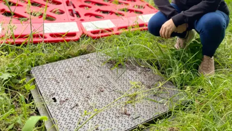 LDRS/Charlie Smith Georgina Heyburn crouching next to a manhole
