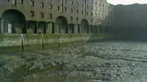 BBC Archives A dock basin with silt lying at the bottom of it. The photo was taken on an old camera.