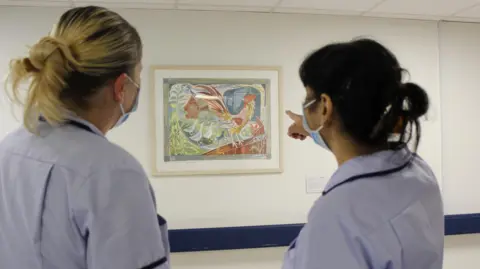 Bedfordshire Hospitals NHS Foundation Trust Two nurses looking at a painting on a hospital wall