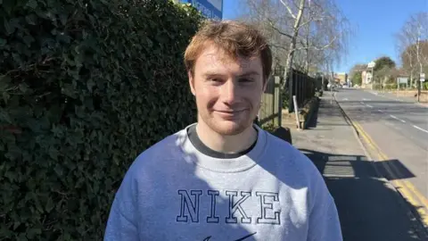 A young man in a grey jumper. 