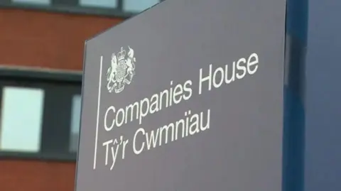 A sign with 'Companies House' and its translation in Welsh written on it. The sign is grey with the writing in white.