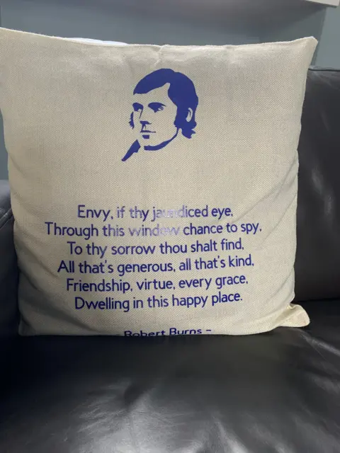 A cushion carrying the words from the Robert Burns poem At Whigham's Inn on it