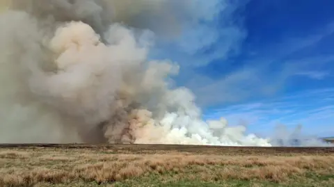 Clouds of white smoke over moorland