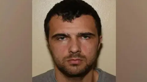 Lancashire Police A police custody image of Elias Morgan, who has black hair and dark stubble, staring into the camera with a blank expression.