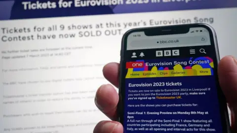 Yui Mok/PA Media Hand hold mobile phone showing Eurovision page