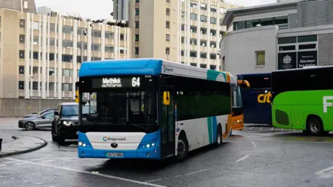 A Stagecoach bus departing a bus station, with buses and cars in the background.