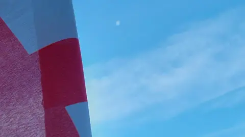 BBC Weather Watchers/Hazlenut A St George cross flag pictured against a blue sky in Penkridge, Staffordshire