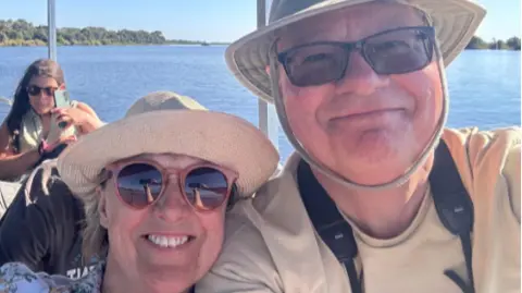 Roland and Shirley Cherry The couple have taken a close-up selfie and both a smiling and wearing hates as they travel on a boat on the river.