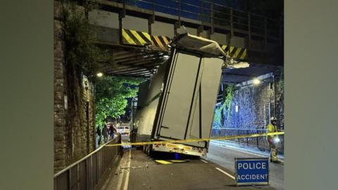 A crashed HGV lorry stuck underneath a railway bridge in Newport