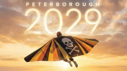 An illustrated picture of the back of Walter Cornelius wearing yellow, black and orange-coloured wings with a skull and crossbones in the middle. He is flying in the sky, which has a golden sunset. "Peterborough 2029" is written in the sky in white.
