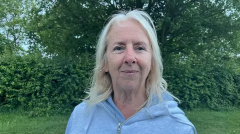 A woman with blonde hair wearing a grey hoodie top