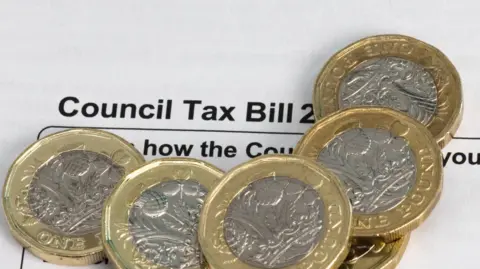 Getty Images Six pound coins sitting on top of a council tax demand.