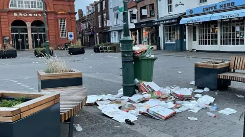 Dozens of pizza boxes lay scattered on the ground around wheelie bins in one of Beverley's main squares