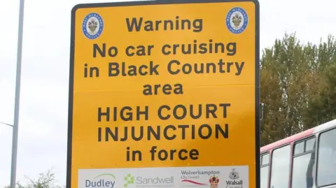 Walsall Council A large yellow sign with a black border. In black writing it states: Warning - no car cruising in Black Country area - High Court Injunction in force.