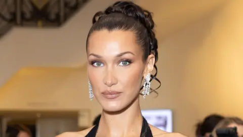 Bella Hadid wearing a black halterneck dress and diamond earrings