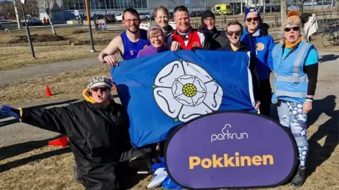 Chris Beresford Runners pose with a Yorkshire flag during Pokkinen Parkrun