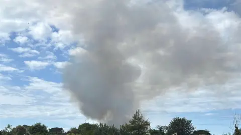 A cloud of smoke in the sky on a clear sunny day in Guernsey.