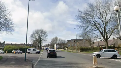 A Google Streeview image of a junction showing a main road with two side roads coming off it. The image contains a number of vehicles coming out from the side roads and traffic heading away from the camera.