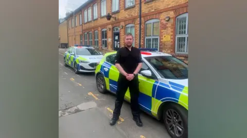 Humberside Police Federation A police officer stands in front of police cars