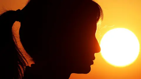 A generic file-photo silhouette a woman looking off into the distance as the sun shines behind her. 