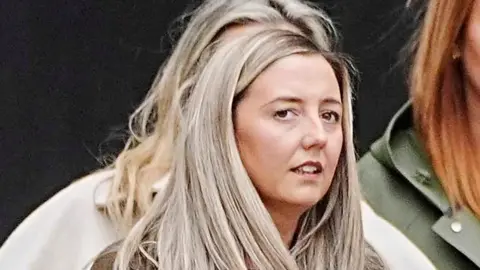 Jenni Stancombe has long blonde hair and is standing in the street outside the public hearing into the Southport attack.
