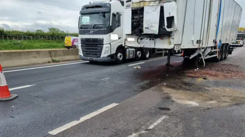 National Highways The large white lorry is seen from the front and there is debris on the tarmac