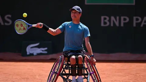 Getty Images Matt Knoesen playing tennis in his wheelchair. He is swinging his racket towards a ball on an orange clay court.