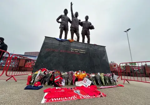 PA Media Tributes left for Denis Law by the statue of Manchester United's Holy Trinity outside Old Trafford: George Best, Denis Law, and Bobby Charlton 