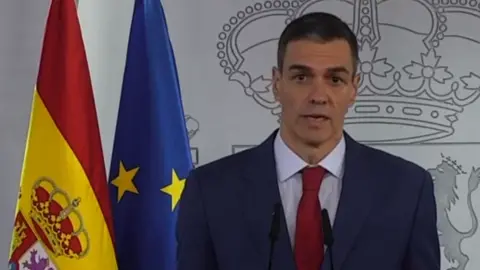 A man in a suit and tie standing next to a yellow and blue flag