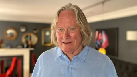 The image shows a man in a blue shirt standing in a restaurant in Bodmin, Cornwall. 